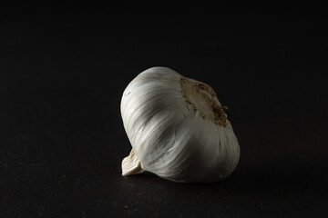 Whole garlic bulb on black background. Minimal food concept.