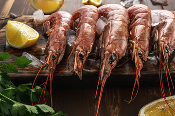 Fresh shrimps on wooden background with lemon slice. Seafood background.