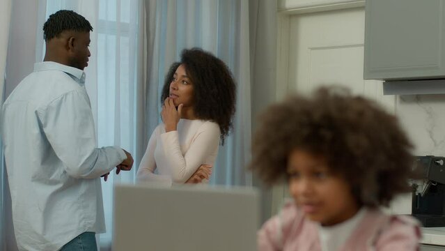 African American couple woman man happy family at kitchen talking wife husband talk blurry little child girl pupil kid daughter studying e-learning online using laptop playing game computer study