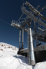 A cable car station high in the mountains under construction. Snowy mountain landscape and construction of a metal structure for a cable car
