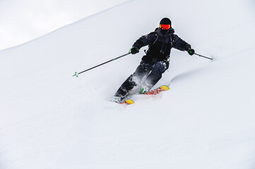 Male skier turns in loose snow, skier downhill downhill at ski resort