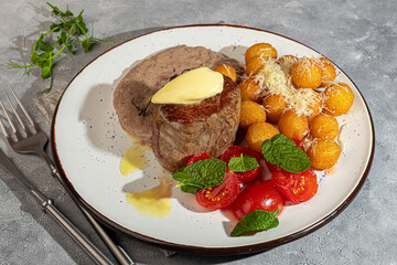 Beef medallion with potato balls and mushroom sauce, topped with a piece of butter.