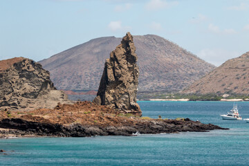 pináculo  de roca en isla  bartolomé con volcán de fondo, galápagos, ecuador