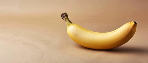   A ripe banana rests atop a table adjacent to a wall featuring shades of brown and white, with a dark spot gracing its summit