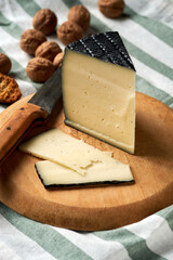 Cheese wedge on wooden board with sliced pieces and nuts