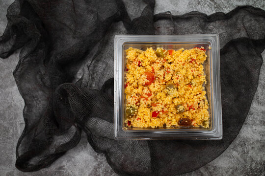 Delicious vegetarian couscous with tomatoes, carrots, zucchini, yellow bell pepper in plastic box
