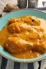 Tasty chicken curry and ginger on wooden table, closeup