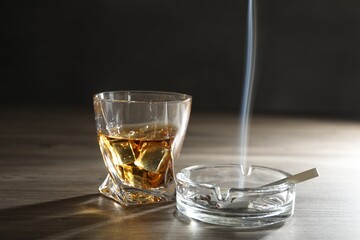Alcohol addiction. Whiskey in glass, cigarettes and ashtray on wooden table