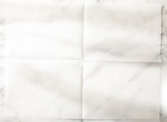 Overhead of folded parchment paper white marble surface