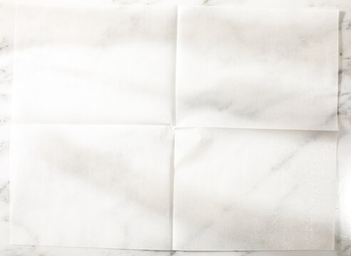 Overhead of folded parchment paper white marble surface