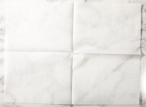 Overhead of folded parchment paper white marble surface