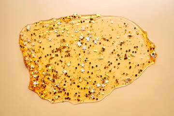 Cosmetic gel with glitter on a beige background.