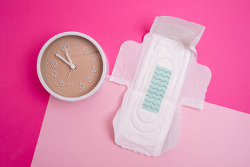 Alarm clock and menstrual sanitary pads. The concept of women's critical days and menstruation. Feminine hygiene. Place for text