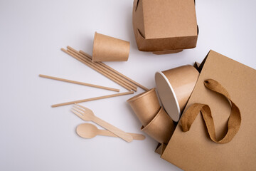 Kraft paper tableware: cups, food boxes, isolated on a light background. A set of various disposable tableware. Recycling and zero waste concept. Mock up
