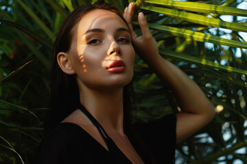 beautiful girl in palm leaves. young woman with Make-up under palm tree - 768987213