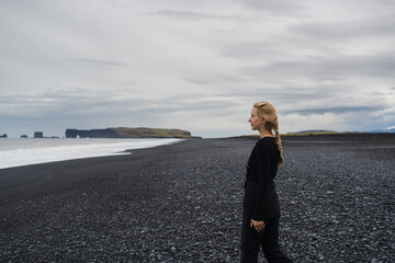 Traveling and exploring Iceland landscapes and travel destinations. Young female tourist enjoying the view and outdoor spectacular scenery. Summer tourism by Atlantic ocean and mountains.