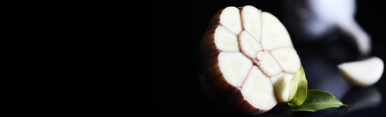Fresh garlic clove on black background. Garlic is rich in vitamins, useful spring, good spices. Garlic sliced on a dark background. Raw sliced garlic.