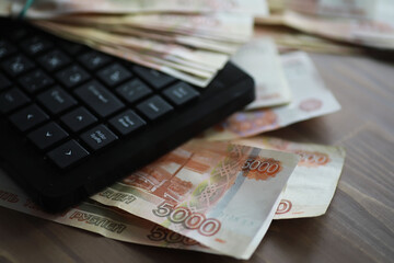 Stacks of 5000 ruble banknotes on the table next to the laptop. Savings and investments in the...