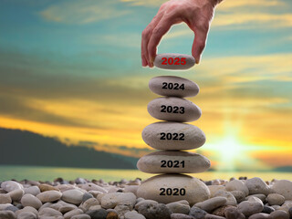 The man's hand leaves a 2025 stone on the blocks. The 2025 concept of economy, work and career. New year anniversary