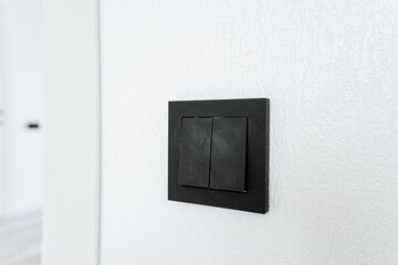 A black light switch is mounted on a white wall in a room with a television set