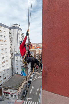 trabajador en altura o trabajador vertical arreglando una fachada frente a un edificio de oficinas