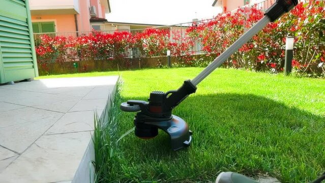 Mowing the grass, string trimmer at work, workflow. Slow motion