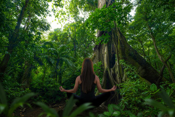 Woman doing yoga in front of rainforest