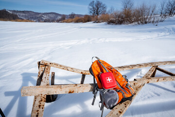 Red First Aid Kit Lying On Hiking Backpack On Snow Background, Hiking Gear, Orange Backpack, Winter...
