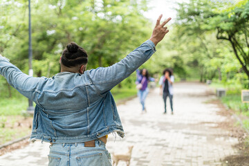 Gay man on his back waving to his friends in a park.