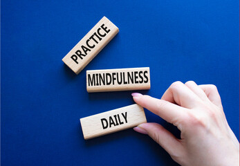 Practice Mindfulness Daily symbol. Concept words Practice Mindfulness Daily on wooden blocks. Businessman hand. Beautiful deep blue background. Medical and Psychology concept. Copy space.