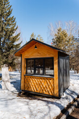 A cozy wooden cottage with a window and door is nestled in the snowcovered park