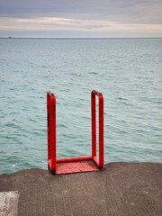 Fototapeta premium close up of a red iron ladder on a lake michigan shore in chicago on an overcast winter day 