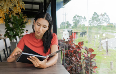 mujer joven latina sentada en un restaurante muy tranquila leyendo un libro  - obrazy, fototapety, plakaty