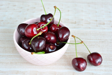 a bowl of cherries with green stems isolated close up   