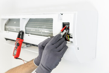 A technician uses a multimeter to check the electrical voltage of an electronic board in a split...