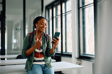 Happy black female student making video call via smart phone at university.