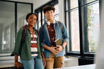 Happy multiracial student couple at university classroom looking at camera.