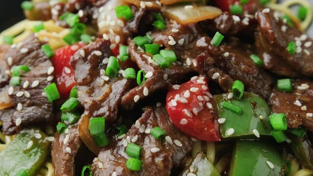 Stir fried beef in black bean sauce with vegetables and noodles. Rotating video