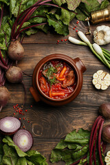 Traditional Russian and Ukrainian soup borscht with beet, beef and mushrooms in clay bowl over...