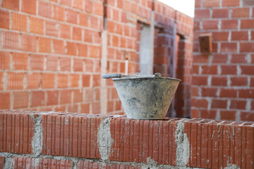 
Mason bucket to mix cement in a building under construction with ceramic bricks. Concept of bricklayer work, masonry, construction, architecture, building industry, real estate ventures.