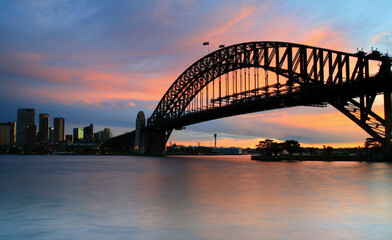 Fototapeta na wymiar Sunset over Sydney Harbor with the skyline and iconic bridge all in view