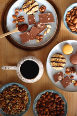 Cup of tea or coffee, cookies, macaroons, chocolate, various nuts and cocoa powder on wooden table. Top view.