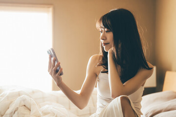 ベッドでスマートフォンを使う女性