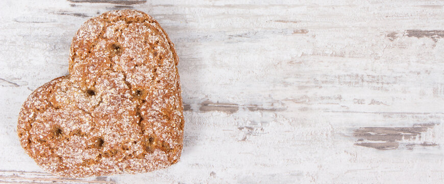 Fresh homemade wholegrain bread in shape of heart for breakfast. Copy space for text on old rustic background