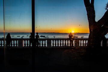Silhouette of unidentified people enjoying the sunset at Praia da Barra in the city of Salvador,...