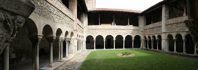 Panoramic view of the Romanesque cloister of the Saint-Lizier cathedral. XII century. Semicircular arches and pillars with beautiful capitals. Ariege. Occitanie. France