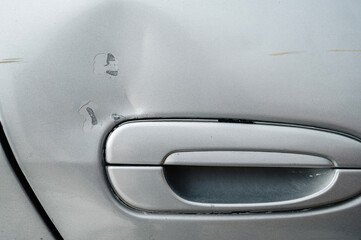 car after an accident with a damaged dented and scratched door on the side close-up - obrazy, fototapety, plakaty
