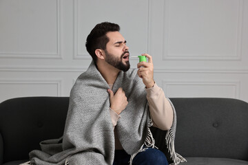 Young man using throat spray at home