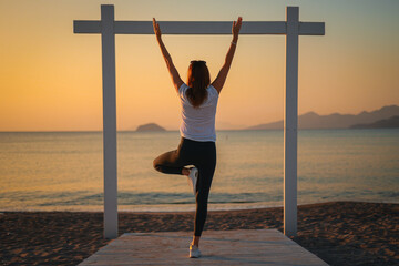 Joga, młoda dziewczyna praktykuje asany na wakacjach nad morzem. Wschód słońca na greckiej wyspie Kos. Ćwiczenia rozciągające, sport na powietrzu.  - obrazy, fototapety, plakaty