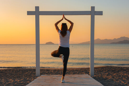 Joga, młoda dziewczyna praktykuje asany na wakacjach nad morzem. Wsch&oacute;d słońca na greckiej wyspie Kos. Ćwiczenia rozciągające, sport na powietrzu. 